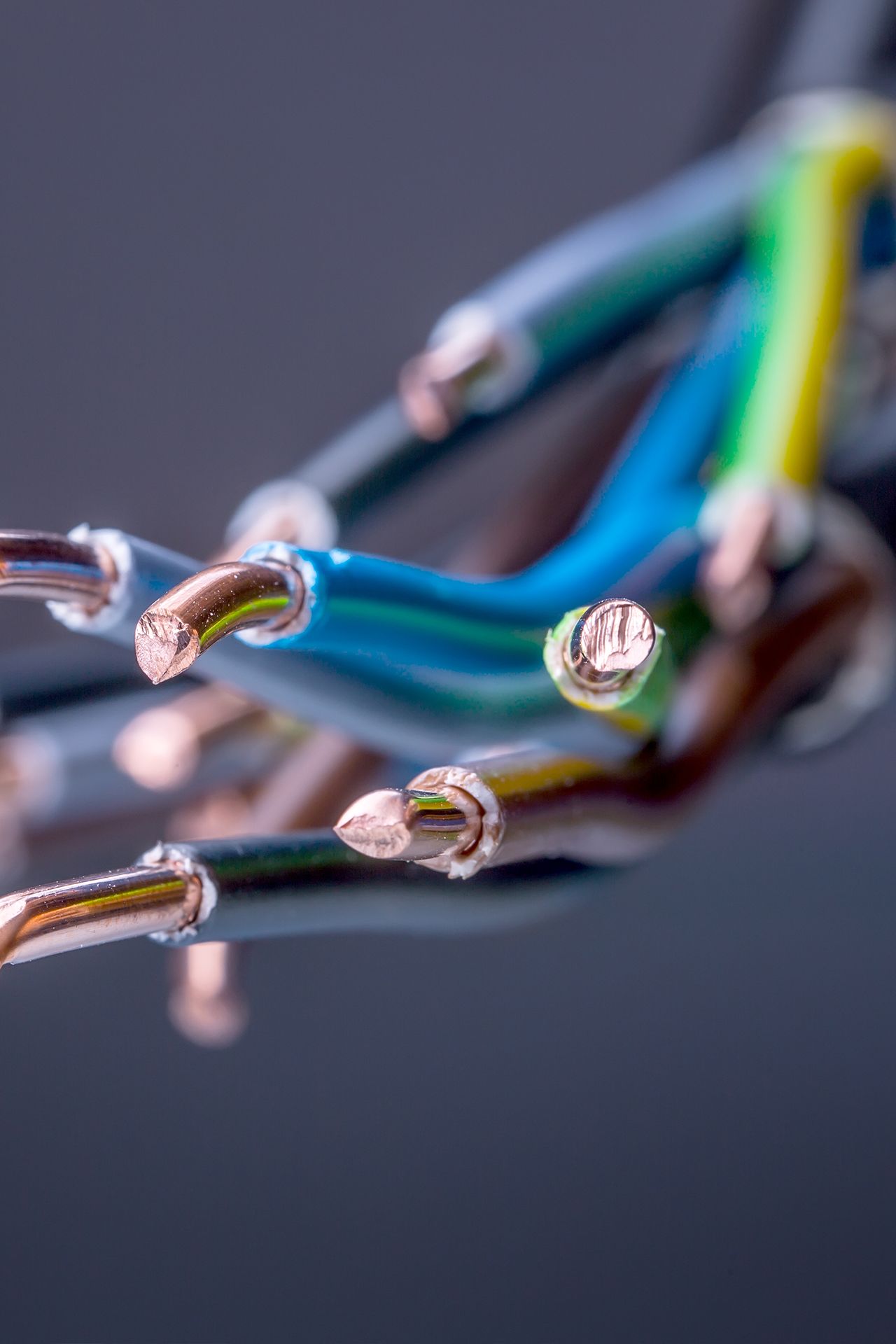 Närbild på avskurna kopparkablar med blå, grön och gul isolering