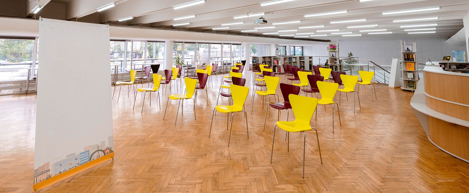 Tom möteslokal med gula och röda stolar på parkettgolv